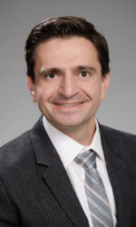 Dr. Habib Rahbar wears a dark suit, white button up, and a grey tie while smiling for a headshot.