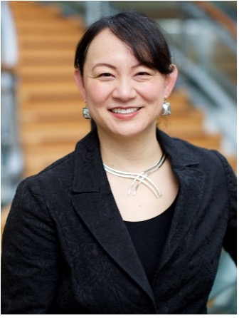 A photo of Dr. Delphine Chen. Dr. Chen wears a black top and blazer with silver jewelry and smiles into the camera.