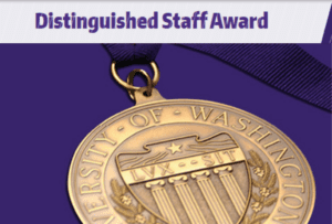 A gold medal embossed with the words: University of Washington on a purple background. Text at the top reads: Distinguished Staff Award.