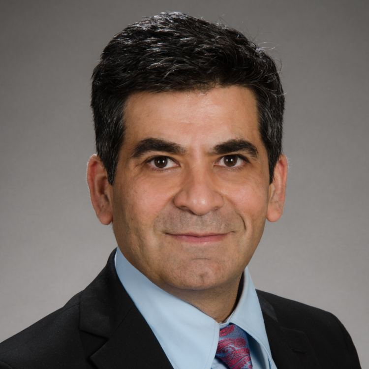 A photo of Dushyant Sahani. Dr. Sahani wears a dark suit, collared shirt, and tie. He looks confidently into the camera.