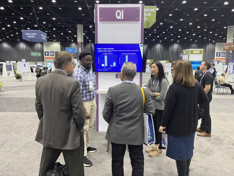 Dr. Michelle Ho and Dr. Adlai Grayson present in front of a screen at the RSNA Annual Meeting. 